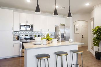 A kitchen with a white counter and bar stools.
